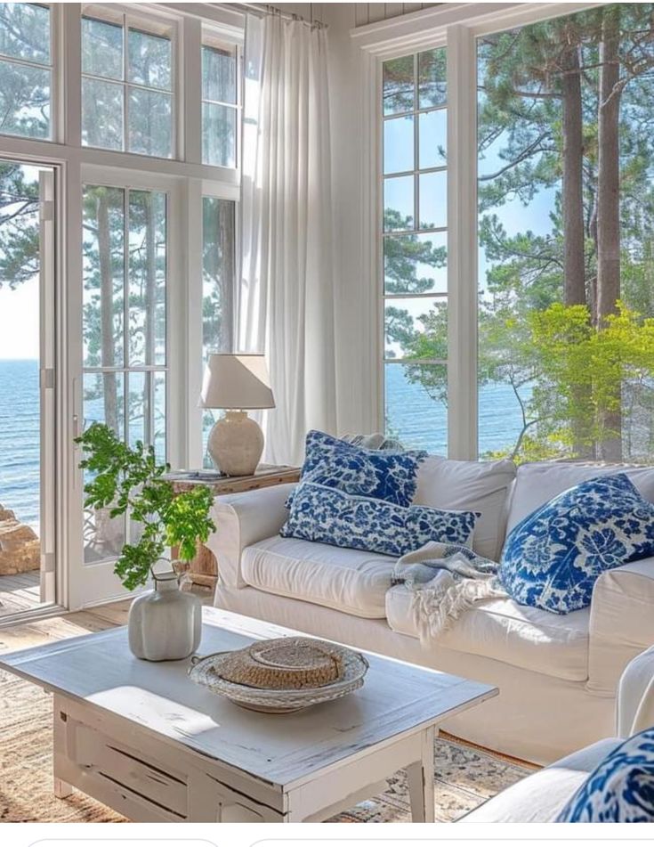 A beautiful summer-inspired living room in white, neutrals, and blue with a lot of natural light flowing in.
