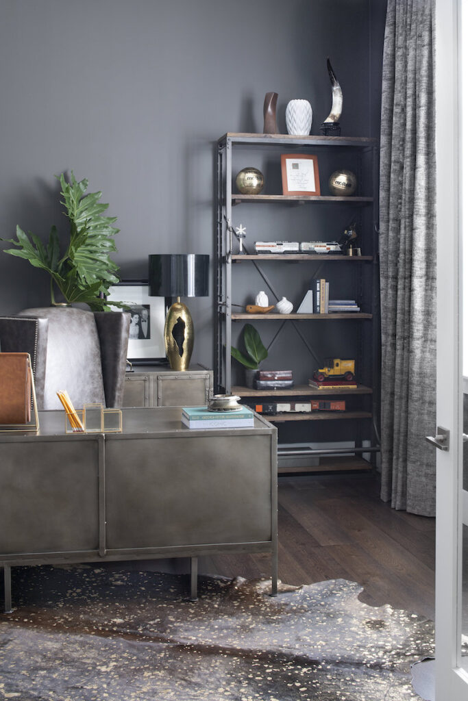 An office painted a dark color to give it a cozy feel with an area rug